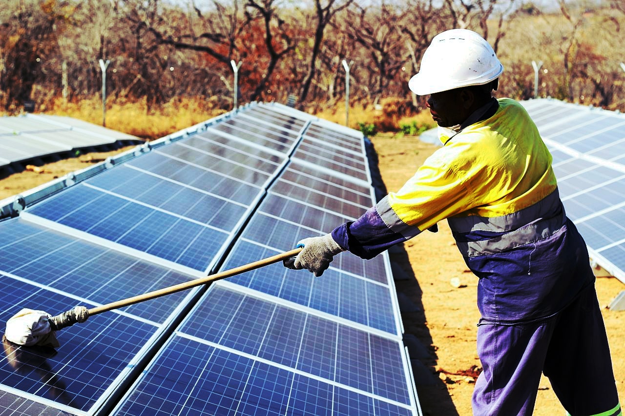 A worker cleaning solar panels at Shanta Gold mine, Tanzania